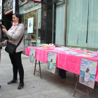 Una voluntaria de la asociación pone un lazo rosa en una de las mesas informativas.