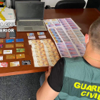 Un guardia civil recuenta el dinero, las tarjetas y el material localizados en el registro. GUARDIA CIVIL
