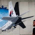 Un joven pasa por delante de un  mural del vuelo MH370 de Malaysia Airlines en Kuala Lumpur el 6 de marzo del 2015.