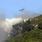 Un helicóptero refresca la zona después de que se declarara el incendio de Tarifa.