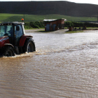 Un tractor circula por la carretera de acceso a la localidad zamorana de Benegiles, anegada tras el desbordamiento del Valderaduey.
