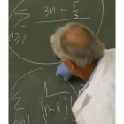 Un profesor escribe en la pizarra durante una clase.