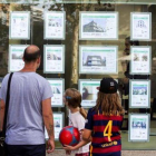 Un hombre y dos niñas observan las ofertas de viviendas en una agencia inmobiliaria del paseo de Maragall de Barcelona.