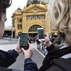 Dos estudiantes prueban el nuevo juego ‘Pokémon Go’ en su móvil en una plaza de Melbourne. JULIAN SMITH