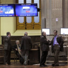 Varias personas ante las pantallas instaladas en la Bolsa de Madrid.