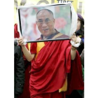 Un monje budista muestra un retrato del Dalai Lama en Londres