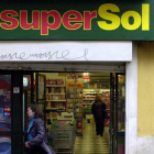 Una cliente sale de un supermercado SuperSol, en una centrica calle de Sevilla.