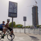 Dos jóvenes pasan bajo un termómetro junto a la Torre Pelli, en Sevilla, que marca 45 grados.