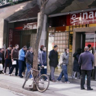 Un grupo de personas hace fila para entrar a una oficina del INAEM.