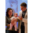 El doctor César García juega con la niña operada, en brazos de su madre.