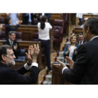 Mariano Rajoy, junto al portavoz parlamentario del PP, Rafael Hernando, aplaude con la bancada popular tras la votación en el pleno del Congreso. Al fondo, de espaldas, Pablo Iglesias recibe la ovación de Podemos y aplaude a su grupo parlamentario.
