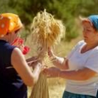 Dos mujeres elaboran un pequeño manojo con pajas de centeno