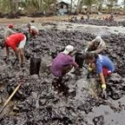 Un grupo de pescadores de Tando recogen petróleo de las playas