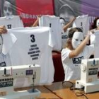 Caras tapadas con máscaras tras máquinas de coser en la protesta contra la explotación