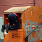 Un hombre rebusca dentro del contenedor de una oenegé.