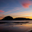 Un hombre observa el amanecer en la playa de Ondarreta de San Sebastián.