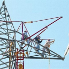 Un grupo de trabajadores preparan la sustitución del tendido de electricidad de una torre de alta tensión.