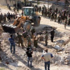 Los soldados revisan los cuerpos de los policías que fueron encontrados en una fosa común.