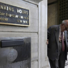 Un anciano griego sale de la sucursal de un banco.