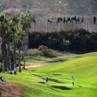 Inmigrantes encaramados en la valla de Melilla, el pasado octubre, mientras varias personas juegan en un campo de golf de la ciudad autónoma.