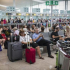 Colas frente al control de seguridad y pasajeros esperando en las instalaciones del aeropuerto de El Prat, ayer.
