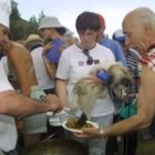 Un cocinero sirve un plato de caldereta a un vecino en la localidad palentina de Velilla