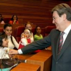 El presidente de las Cortes saluda a uno de los niños participantes en el acto