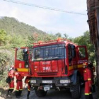 Un helicóptero descarga agua en una ladera del monte de roble situado justo por encima de las casas
