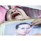 Una mujer llora a las puertas del hospital con la la foto del rey Bhumibol.