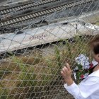 Una mujer coloca flores mientras observa los restos del convoy siniestrado.
