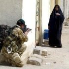 Un soldado británico apunta con su arma a una anciana en una calle de Umm Qasr, en el sur iraquí