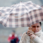 Una mujer se protege del viento y la lluvia durante un temporal. EFE / LAVANDEIRA
