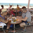 Dos turistas utilizan el móvil en una playa de Barcelona.