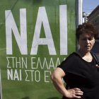Una mujer espera el autobús junto a un cartel que pide el voto positivo en el referéndum, en el que se lee: "Sí a Grecia, sí al euro".