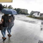Dos mujeres se resguardan de la lluvia en León
