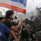 Manifestantes antigubernamentales se enfrentan a los agentes antidisturbios cerca de la sede del Gobierno en Bangkok, este viernes.