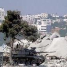Un tanque israelí permanece apostado junto al edificio de la autoridad palestina destruido en Hebrón