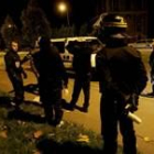 Los policías interrogan a unos jóvenes después de que varios coches fueran incendiados por vándalos