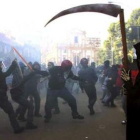 Un policía antidisturbios golpea a un manifestante.