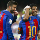 Leo Messi celebra junto a Luis Suárez, ante la mirada de Gerard Piqué, el quinto gol del equipo en el partido ante el Betis. QUIQUE GARCÍA