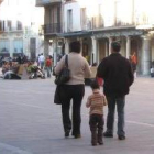 Una pareja camina en compañía de un niño por la plaza Mayor