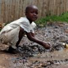 Una niña se lava las manos en un charco, una de las principales fuentes de enfermedades