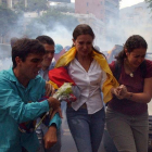 La opositora María Corina Machado, acompañada por simpatizantes, escapa de los gases lacrimógenos lanzados por la policía, este martes en Caracas.