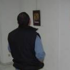 Un hombre contempla algunas de las fotografías sobre retablos expuestas en la biblioteca