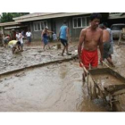 Varios hombres tratan de remover el fango de una casa afectada por las inundaciones hoy, en Marikina