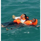Dos supervivientes del naufragio flotan en el océano.