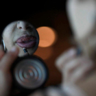 Una mujer que ejerce la prostitución retoca sus labios ante un espejo de mano.