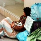 Un mendigo descansa en una calle al lado de sus pertenencias, en una fotografía de archivo