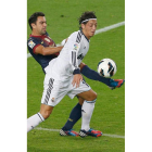 Xavi Hernández intenta robar la pelota al centrocampista alemán del Real Madrid Mesut Özil.