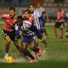 Melero es entrado por un adversario. Jugar en un campo encharcado se hizo difícil.